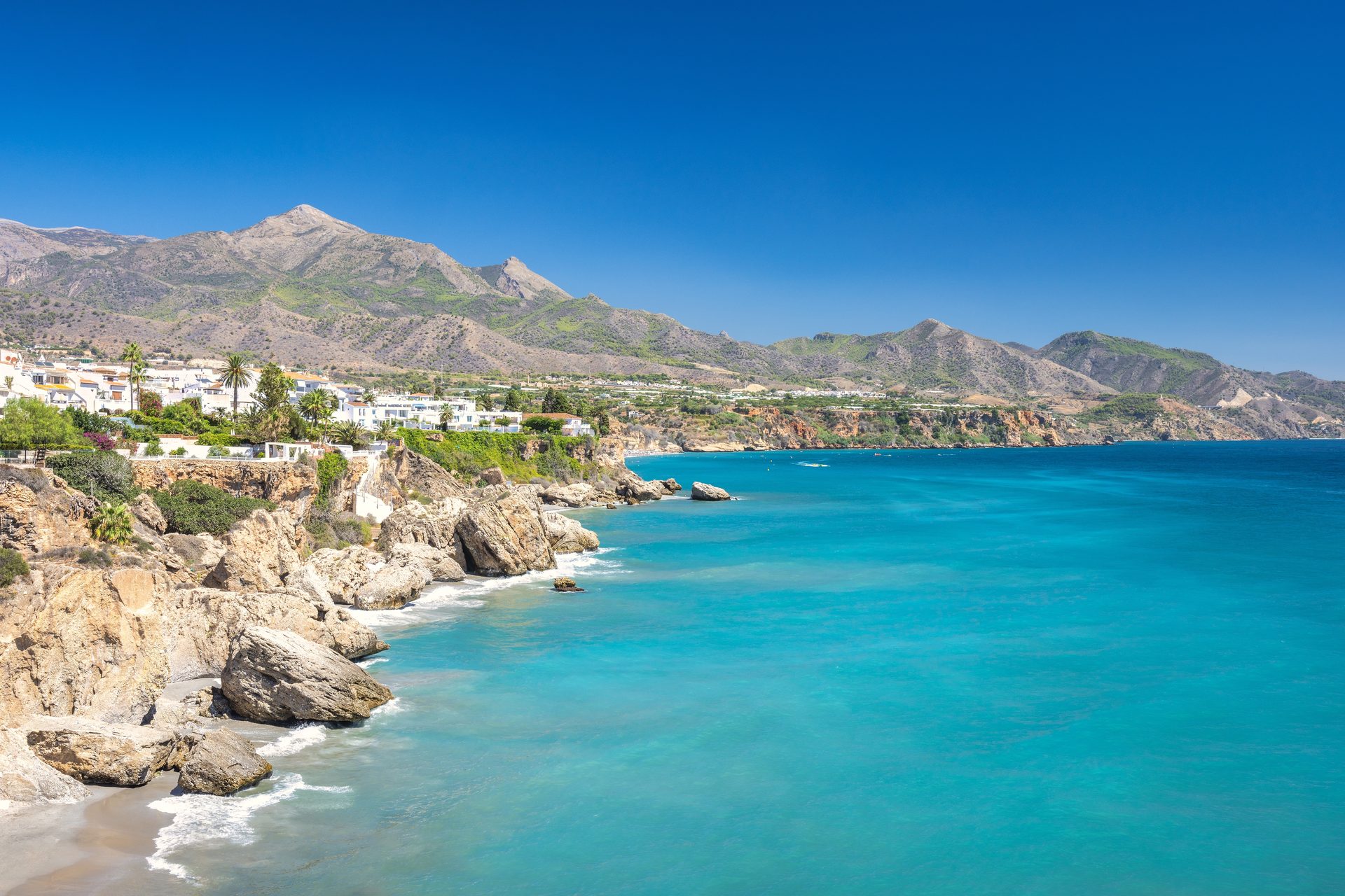 Oceanfront room with stunning blue sea and mountain views, featuring a balcony and modern amenities.